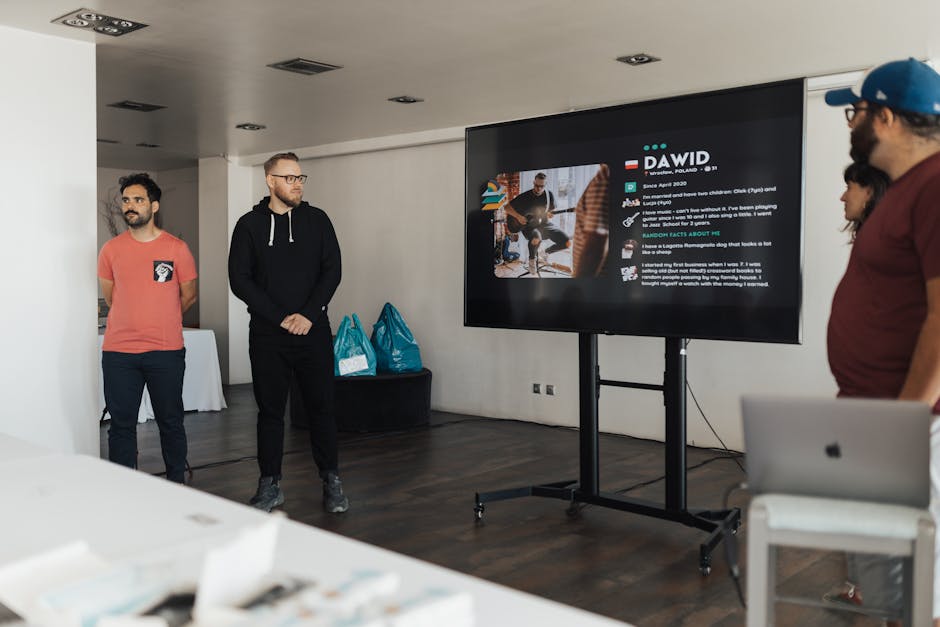 Business team giving a presentation in a modern office environment with a digital display.