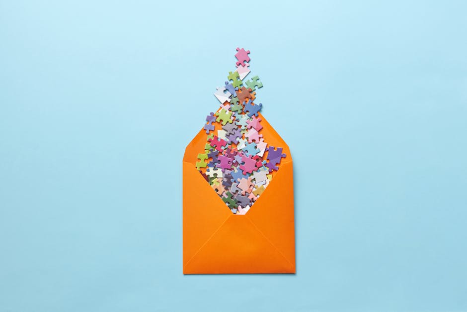 A vibrant collection of puzzle pieces spilling out of an orange envelope on a light blue background.