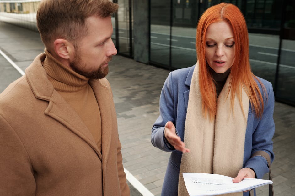 Two professionals engaged in a serious discussion, reviewing documents outdoors.